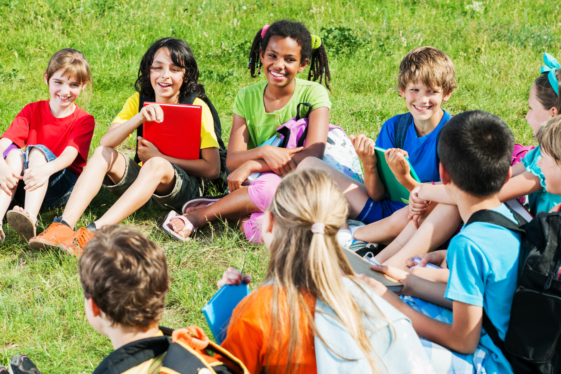 School children sitting in nature and communicating.